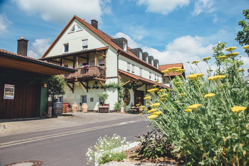ein Gebäude auf einer Straße mit gelben Blumen in der Unterkunft Weingut Leininger Ferienwohnungen in Eibelstadt