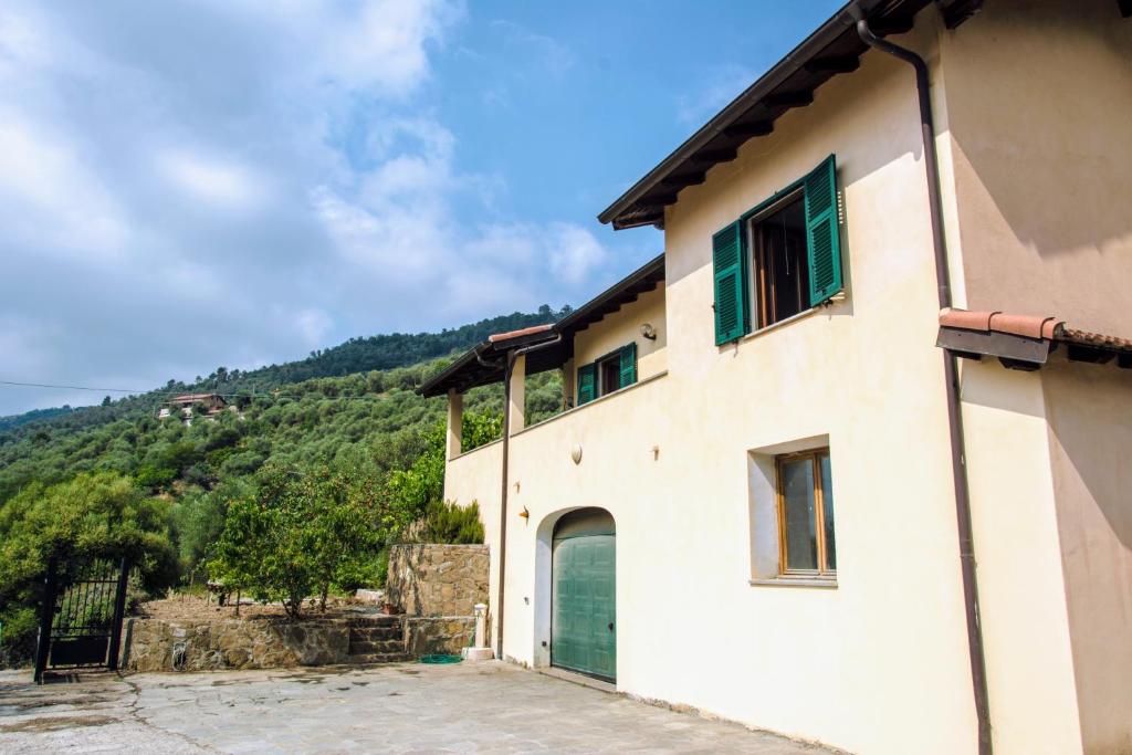 a building with a green door and a mountain at Le Ortensie in Dolceacqua