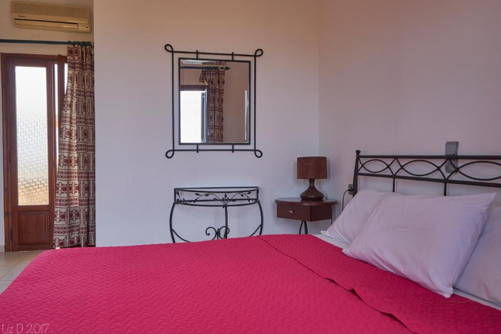 Dimitra Apartments في سيتيا: غرفة نوم بسرير وبطانية حمراء ومرآة