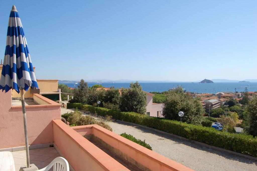 a balcony with an umbrella and a view of the ocean at Solanha monolocale n.4 in Cavo