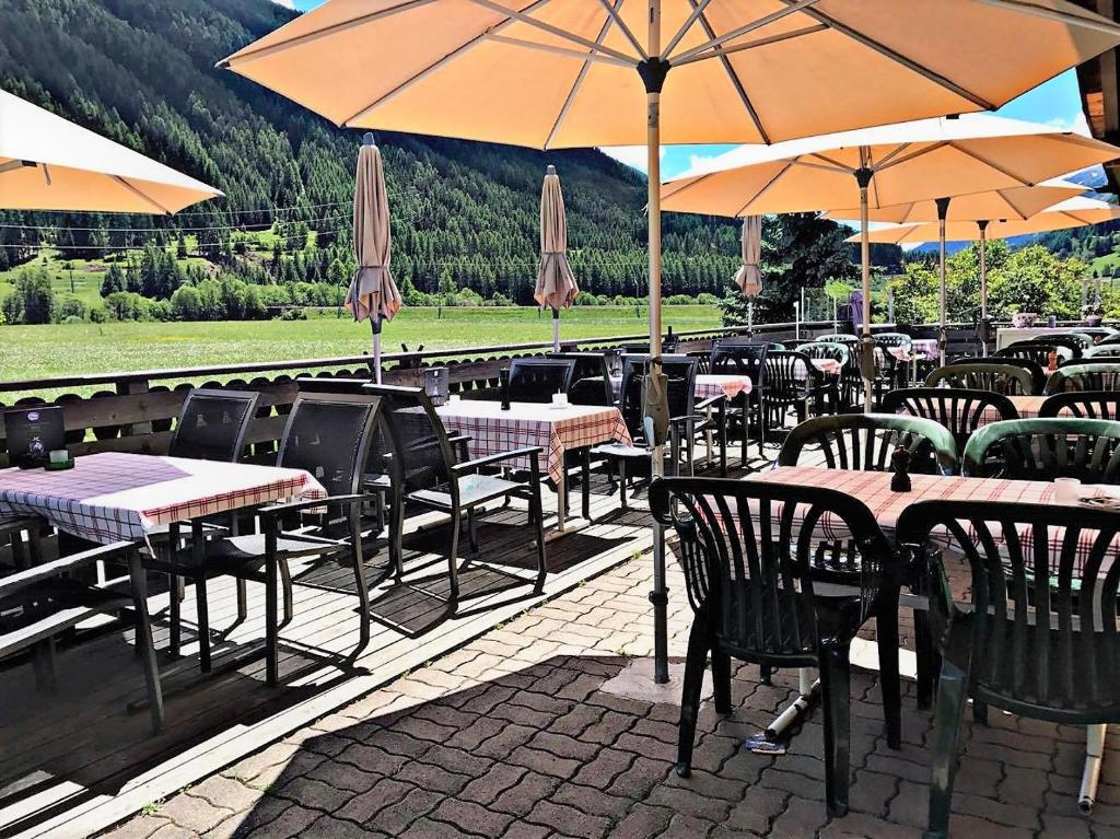 a restaurant with tables and chairs with umbrellas at Hotel Pizzeria Selva in Zernez