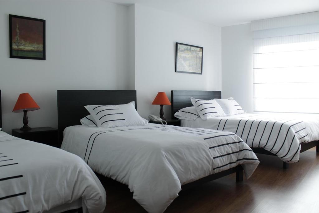 1 dormitorio blanco con 2 camas y sábanas blancas en Hotel Real Estación, en Bogotá