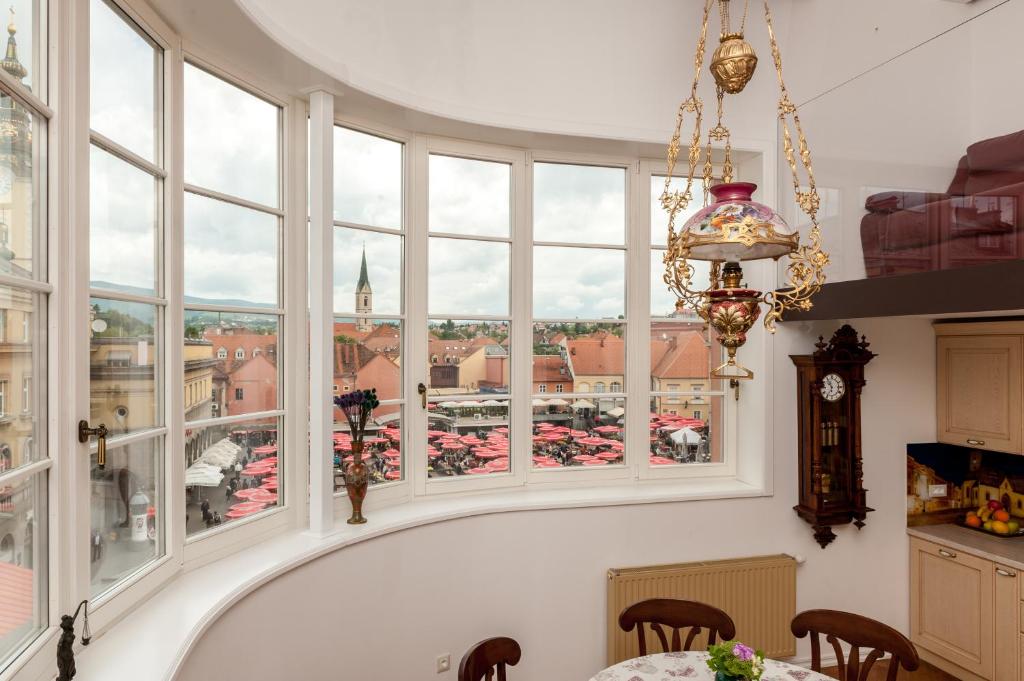 a kitchen with large windows and a table and chairs at Main Square penthouse in Zagreb