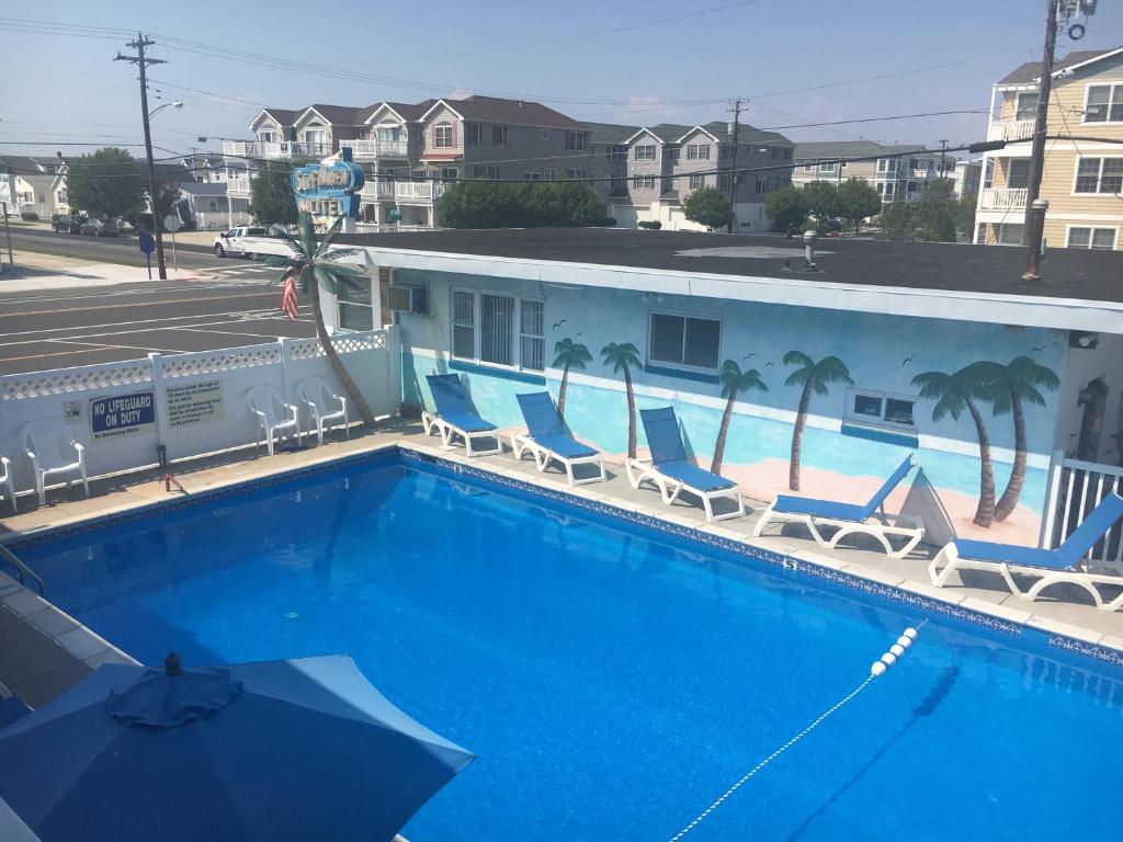 a large swimming pool with chairs and an umbrella at Surf Haven Motel in North Wildwood