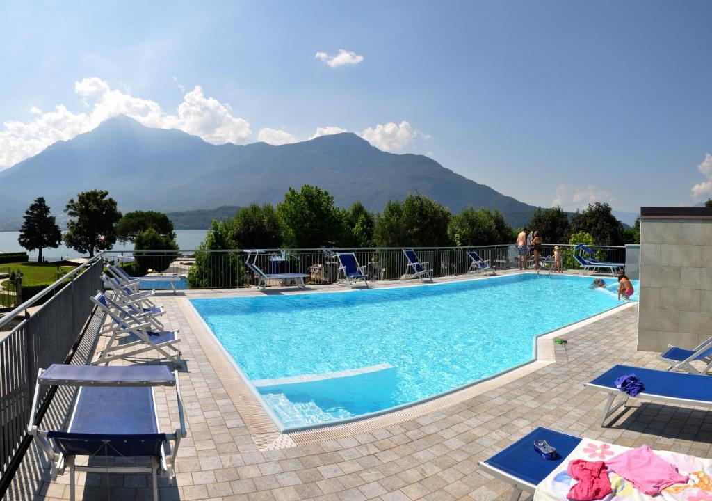 a swimming pool with chairs and mountains in the background at Camping Villaggio Paradiso in Domaso