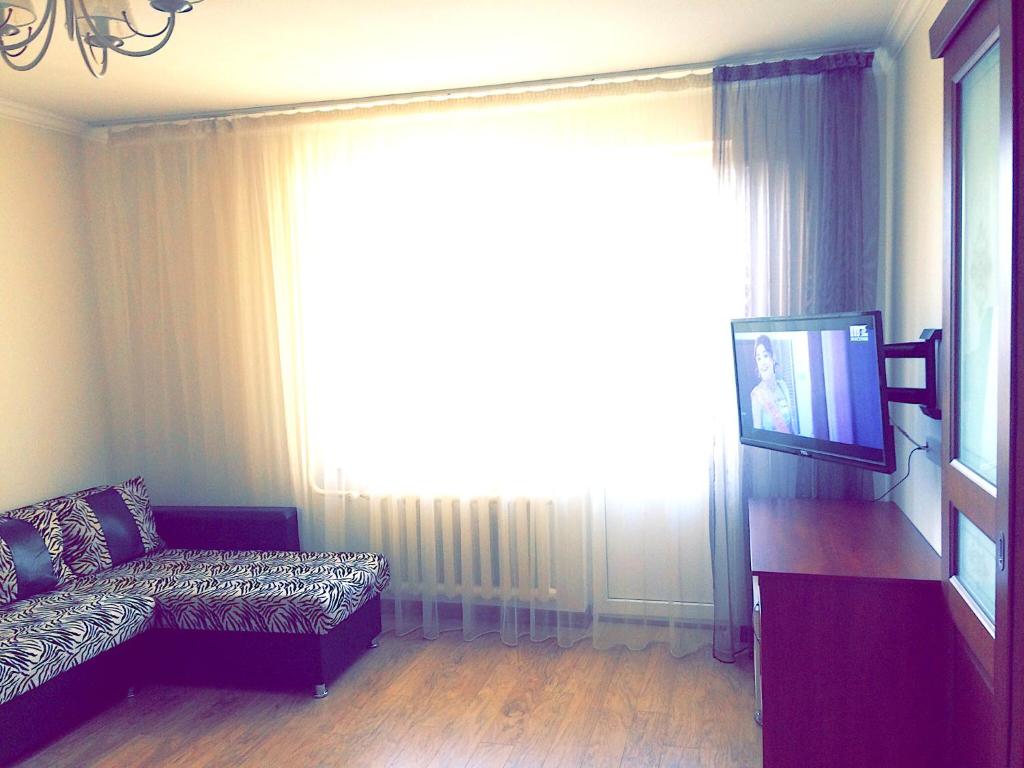 uma sala de estar com um sofá e uma grande janela em Khan Shatyr Apartment em Astana