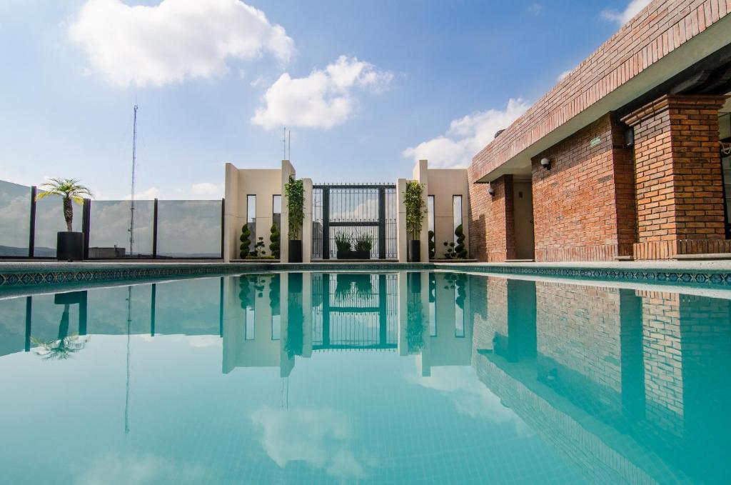 una piscina con acqua blu di fronte a un edificio di Hotel Real Plaza a San Luis Potosí