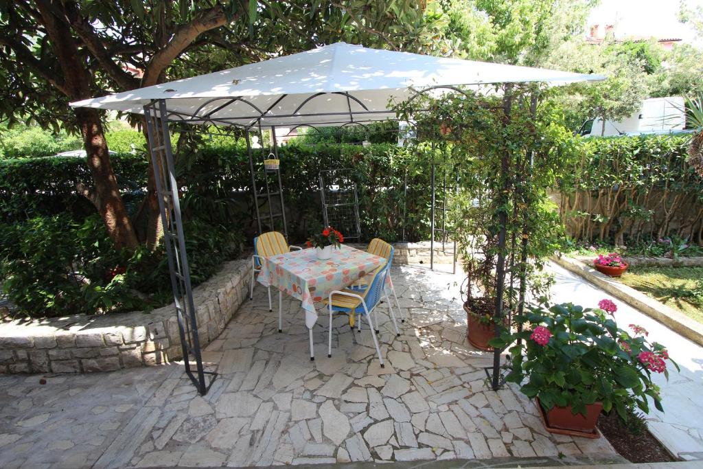 una mesa y sillas bajo una sombrilla en un jardín en Apartments Lara, en Rovinj