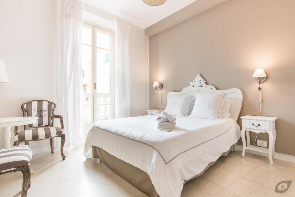 a white bedroom with a bed and a chair at B&B La Sosta degli Artisti in Pietrasanta