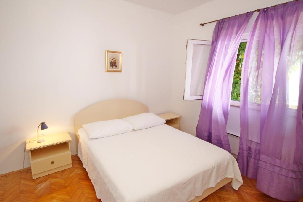 1 dormitorio con 1 cama y una ventana con cortinas moradas en Apartment Toncica, en Omiš