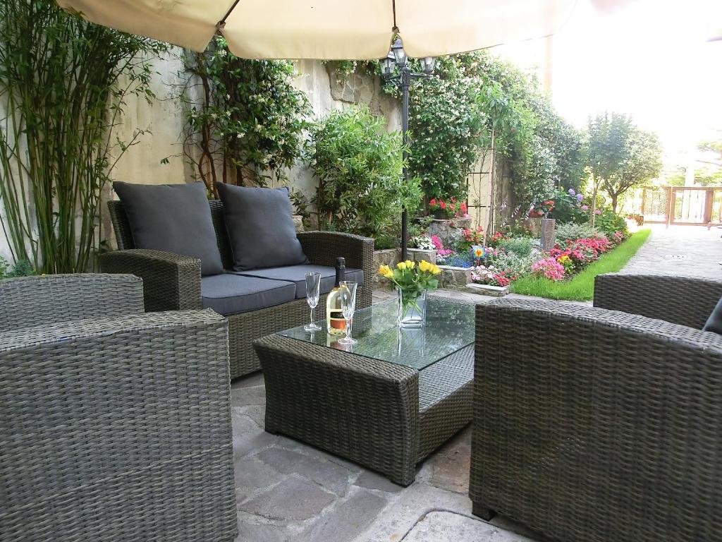 un patio con sedie in vimini, un tavolo e un ombrellone di Le Rose a Trieste