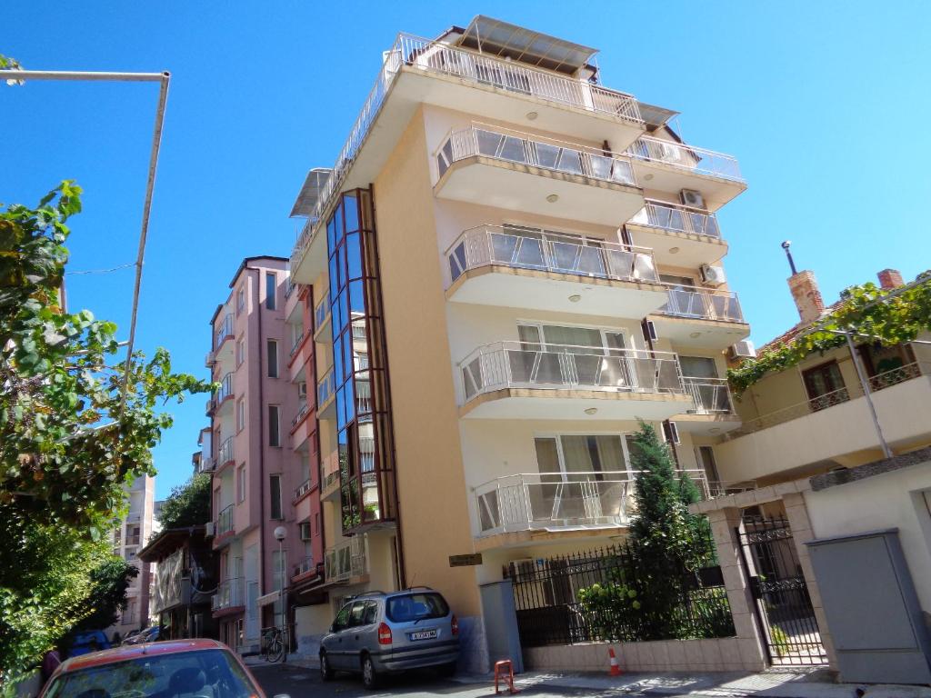 a tall building with cars parked in front of it at Стаи за гости" Герови" in Nesebar
