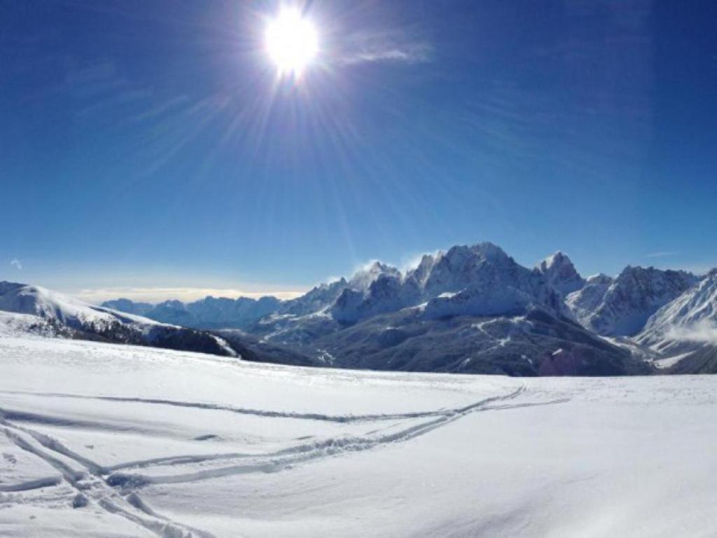 una montaña cubierta de nieve con el sol en el cielo en Appartamento Comelico Dolomiti, en Candide