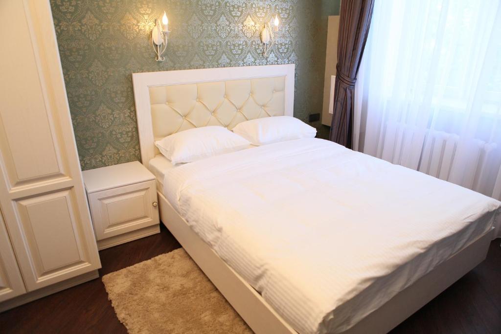 a bed with white sheets and pillows in a bedroom at D'Rami in Almaty