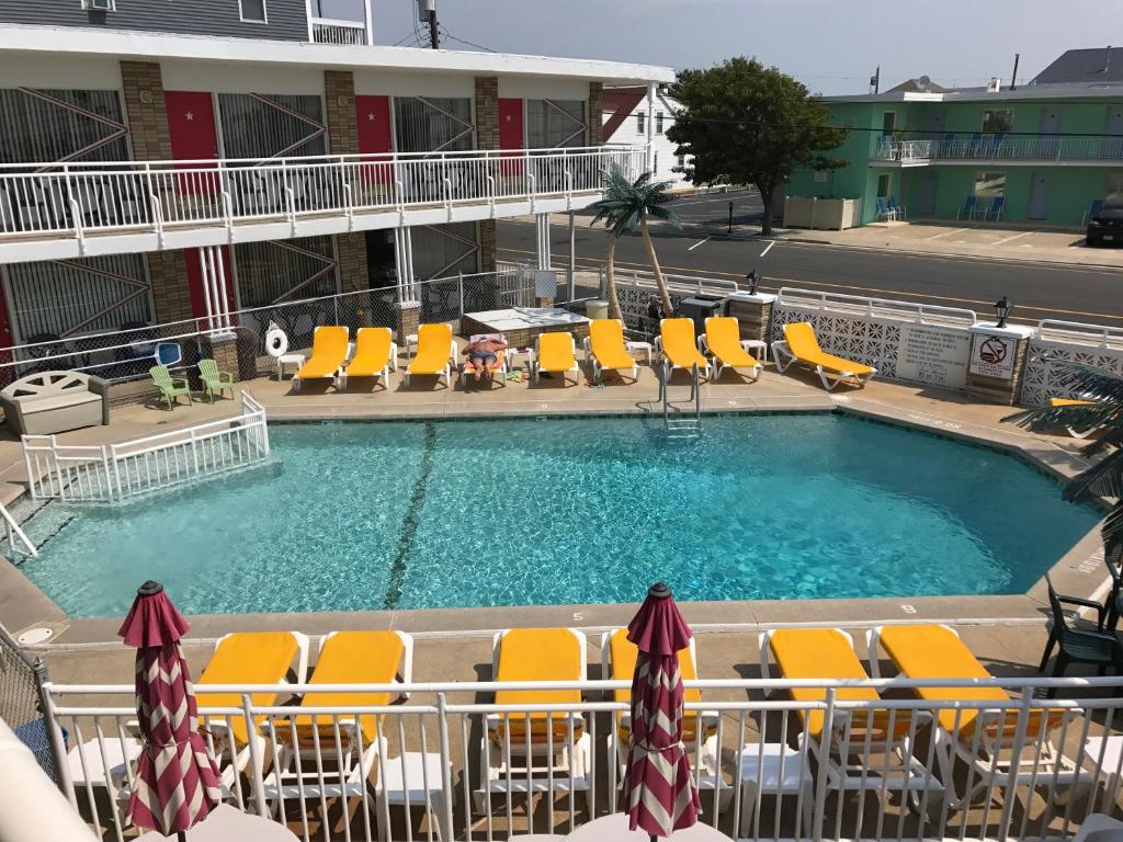 una piscina en un hotel con tumbonas amarillas en Starfire Motel en Wildwood