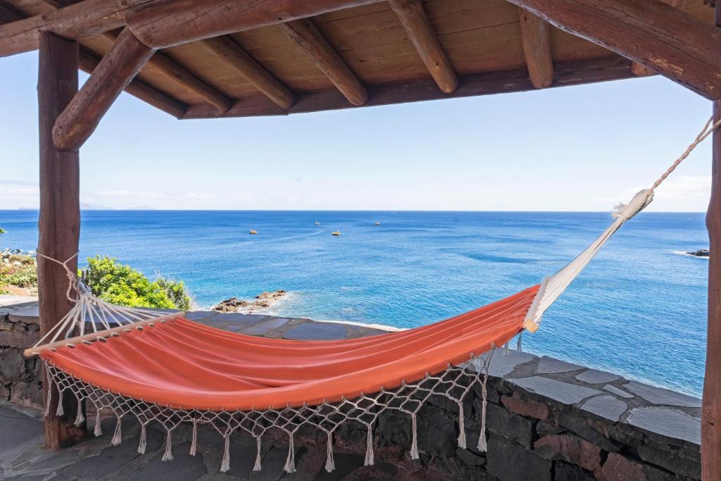 an orange hammock hanging from a roof overlooking the ocean at Vila Cais da Gaivota in Caniçal