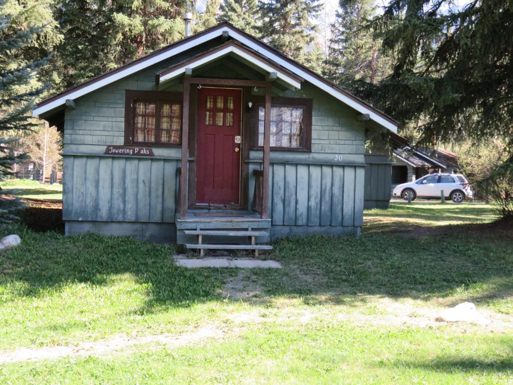 a small house with a red door in a yard at Rundle Chalets in Canmore