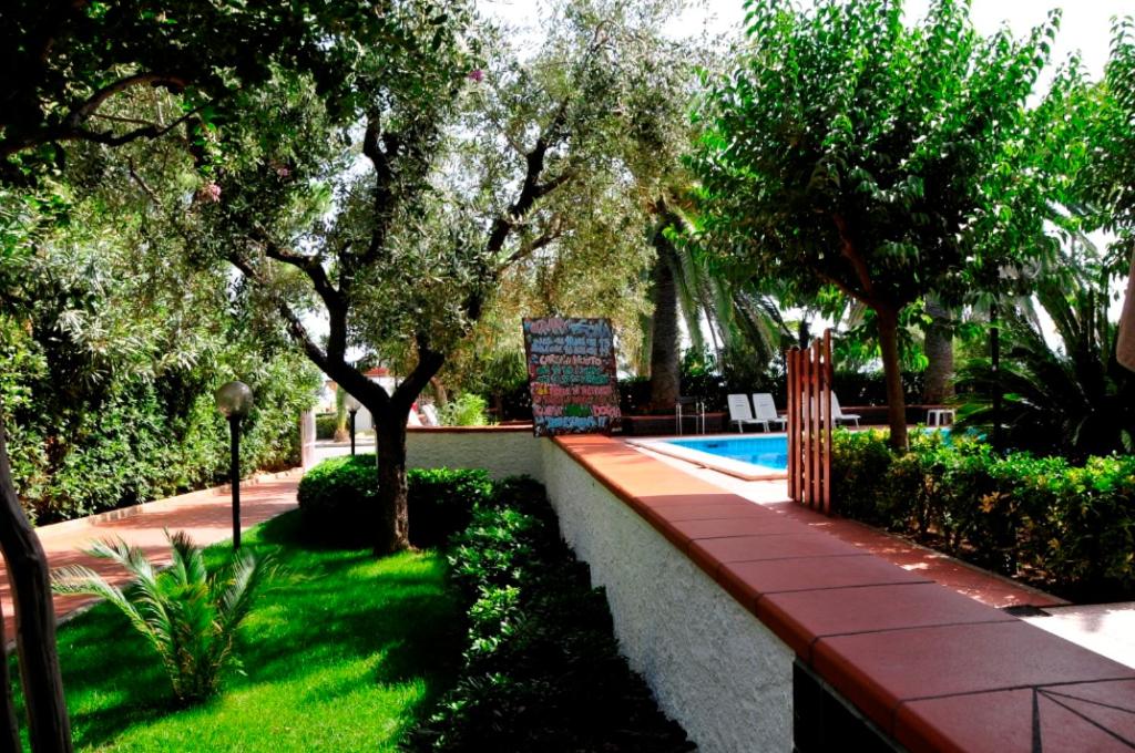 un giardino con piscina, alberi e prato di Hotel Haway a Martinsicuro
