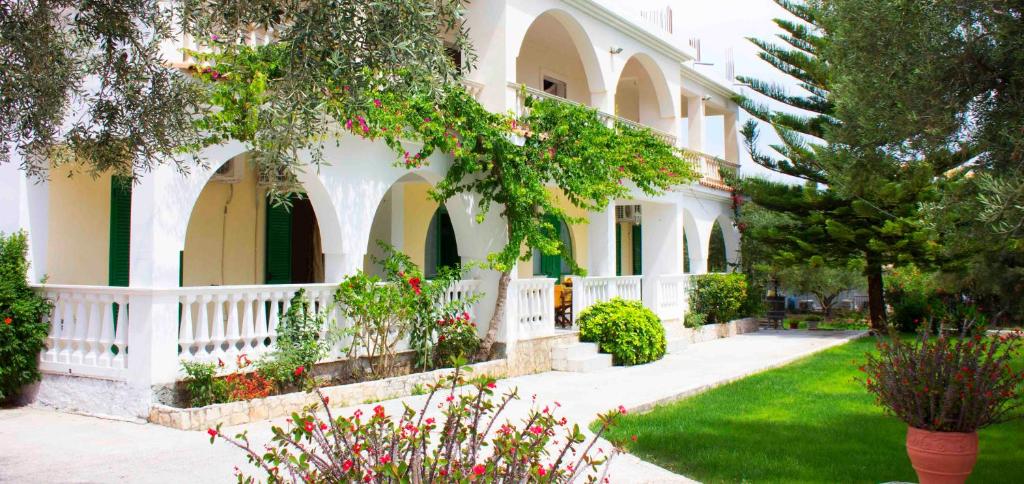 a white house with a white fence and a yard at Mersina Apartments in Keri