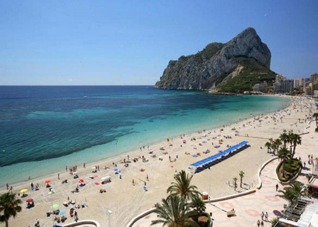 Grupa ludzi na plaży z widokiem na ocean w obiekcie Appartemento ALAMO PLAYA LA FOSSA w mieście Calpe