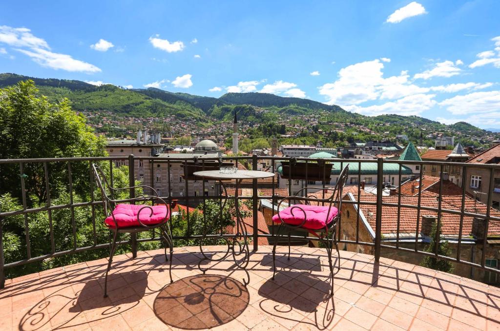 eine Terrasse mit rosa Stühlen und einem Tisch auf einem Balkon in der Unterkunft Apartments Diva in Sarajevo