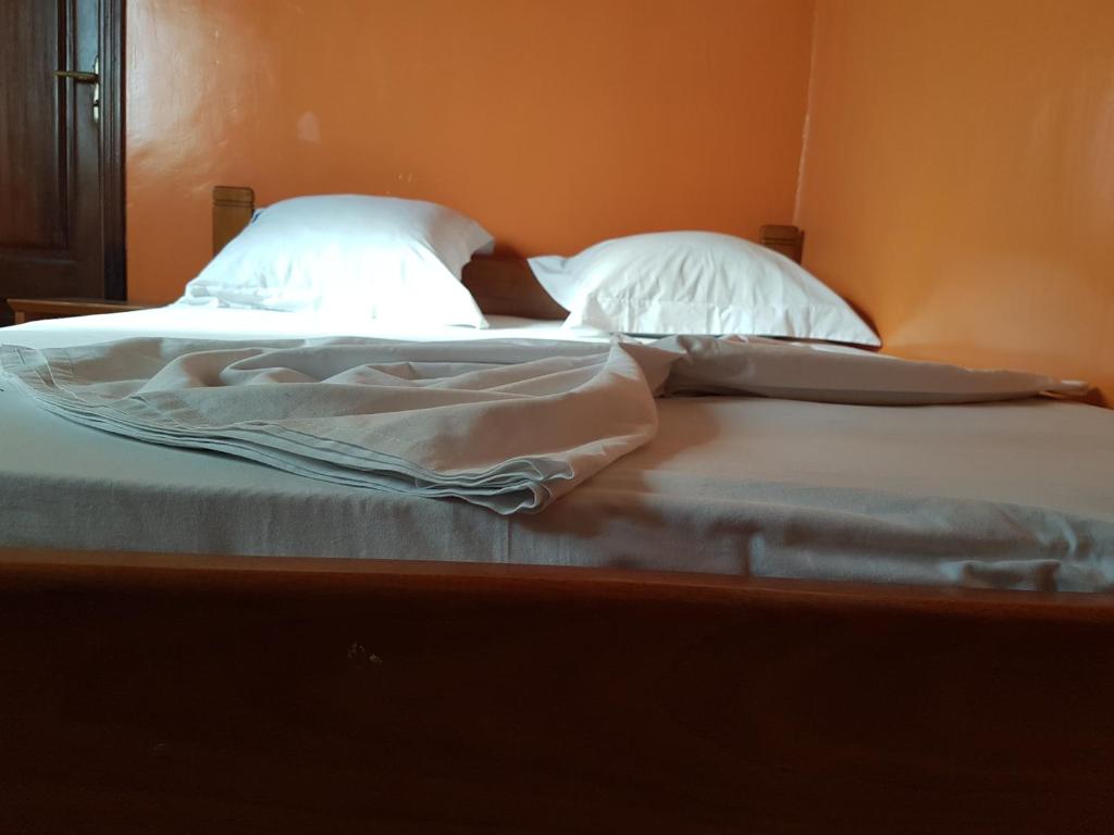 Maison Rose في دوالا: سريرن مع ملاءات بيضاء ووسائد في غرفة النوم