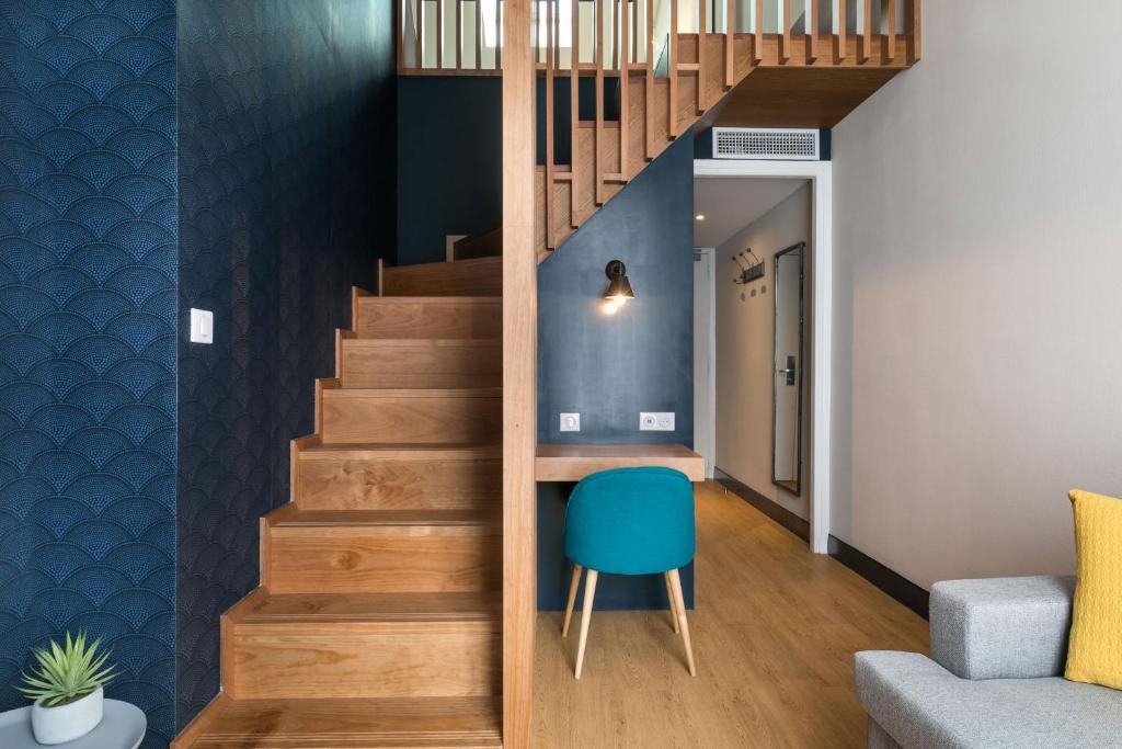 a staircase with a blue chair in a living room at Hotel Nap By HappyCulture in Nice