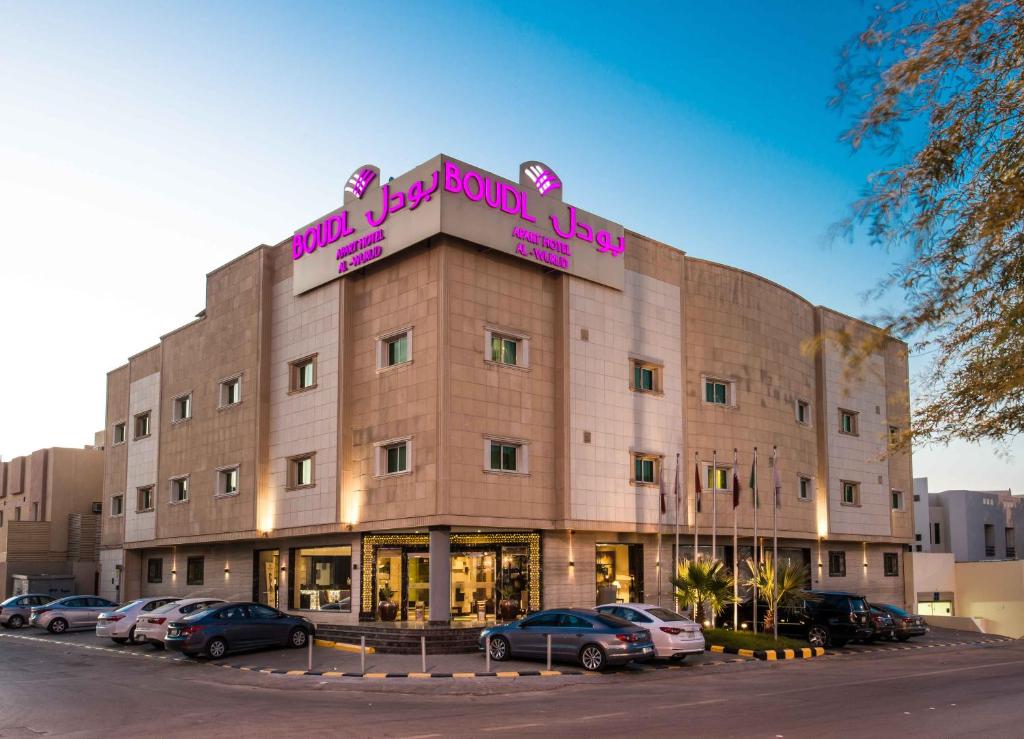 a large building with cars parked in a parking lot at Boudl Al Woroud بودل الورود in Riyadh