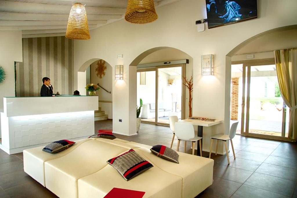 sypialnia z dużym łóżkiem i kobieta stojąca przy ladzie w obiekcie Eliantos Boutique Hotel & Spa w mieście Santa Margherita di Pula