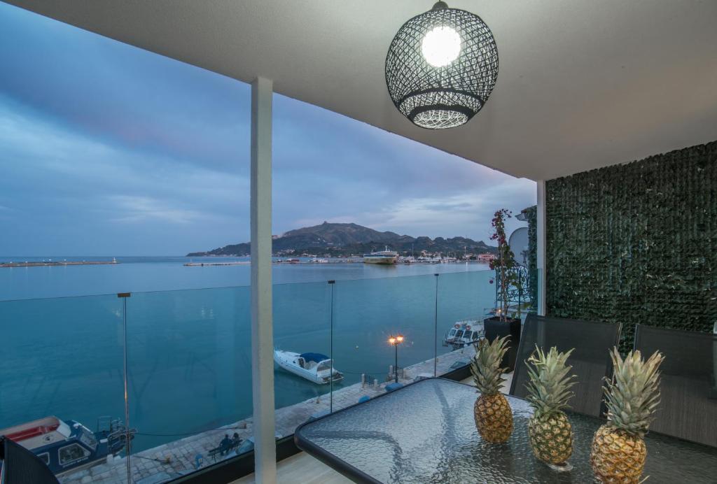 een kamer met een glazen tafel en uitzicht op het water bij Pineapple Seaside Suite in Zakynthos