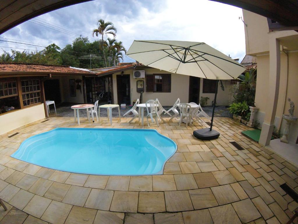 a swimming pool with an umbrella and a table and chairs at Pousada Mercador in Paraty