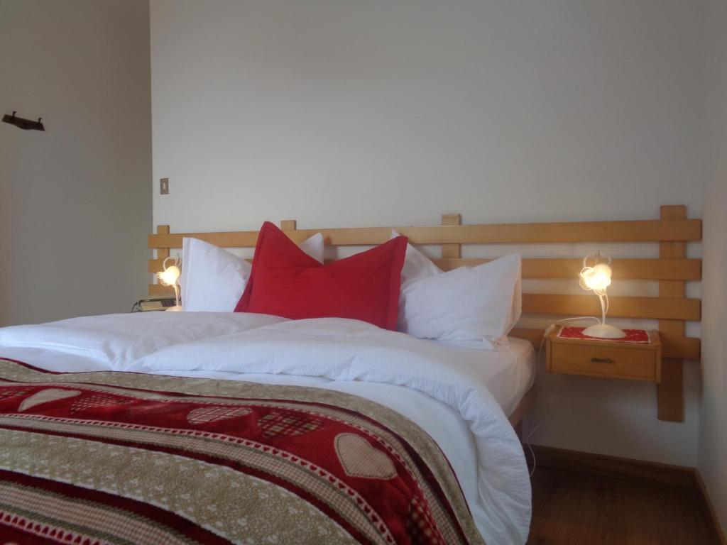 a bedroom with a large bed with red pillows at Hotel Garni Suisse in San Martino di Castrozza