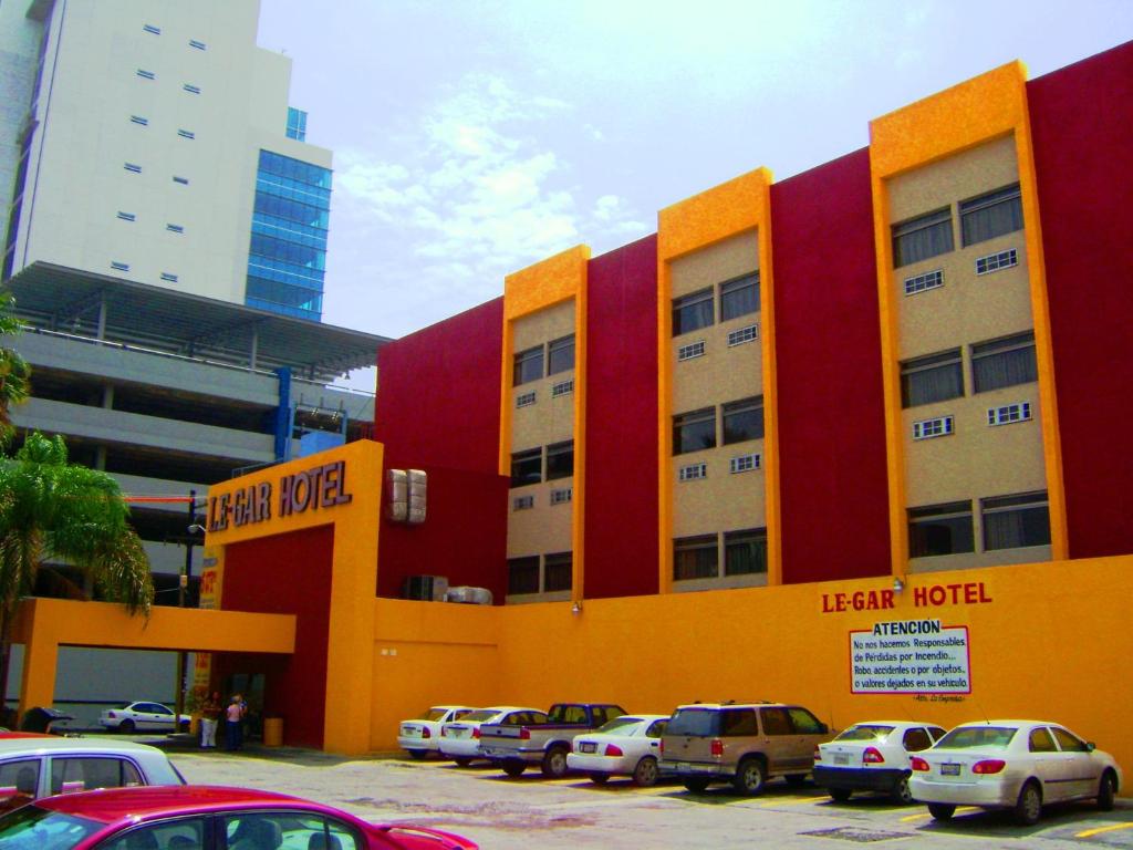 a building with cars parked in a parking lot at Hotel Le-Gar in Monterrey