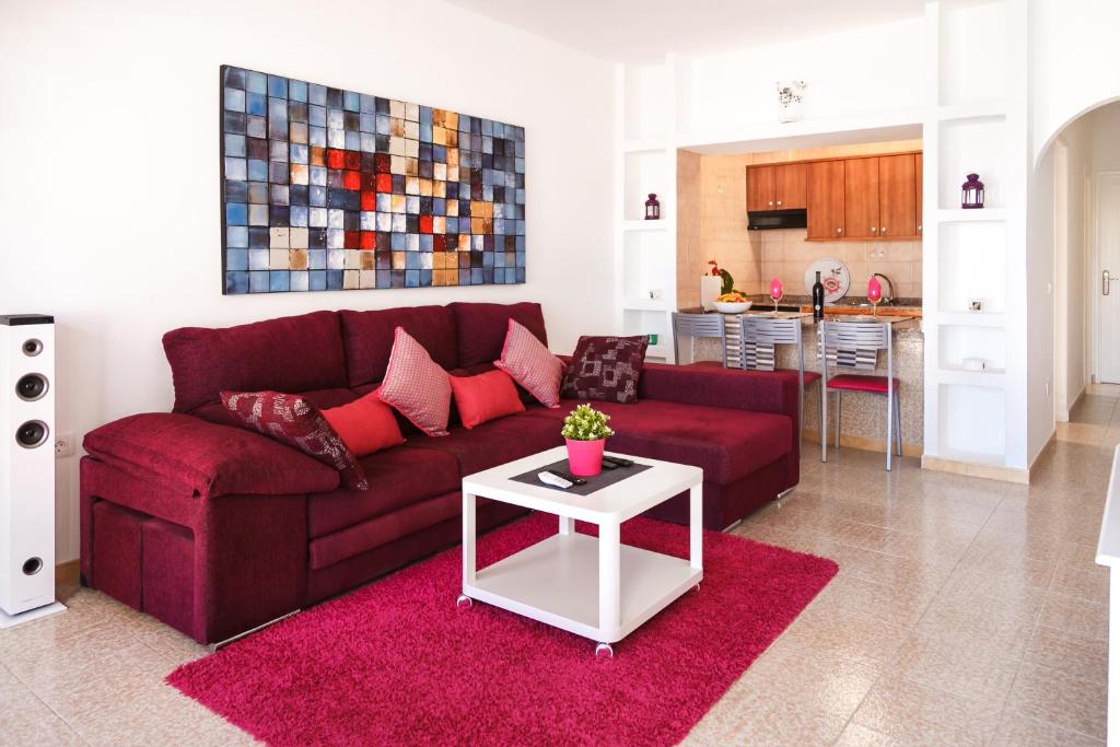 プエルト・デル・カルメンにあるApartamento Fillaのリビングルーム(赤いソファ、白いテーブル付)
