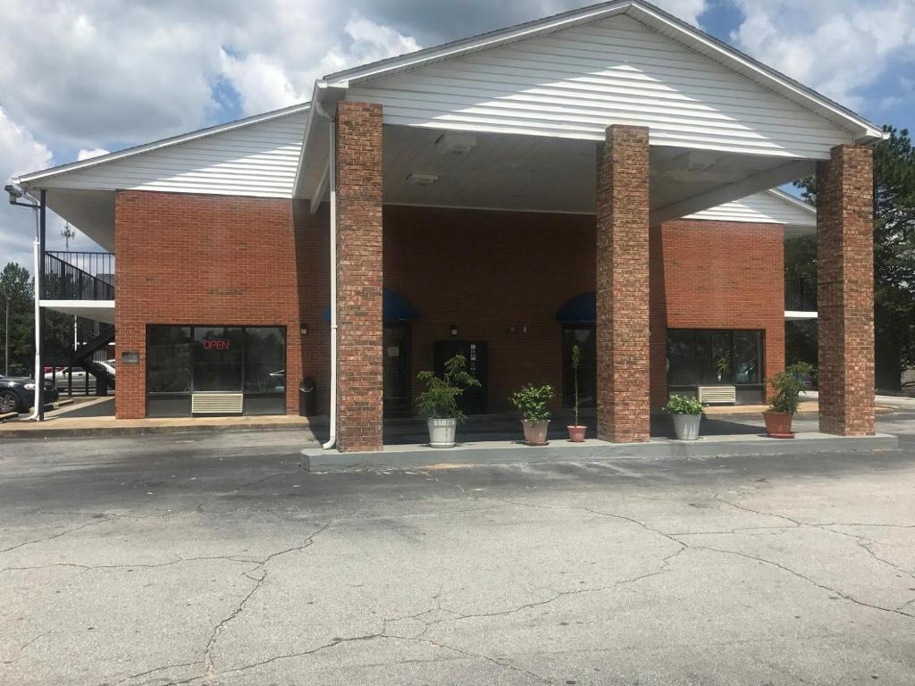 a brick building with potted plants in a parking lot at Gulf American Inns in Decatur