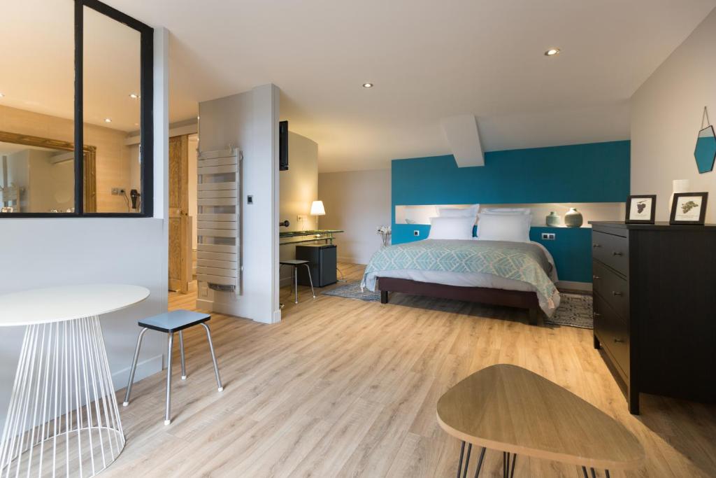 a bedroom with a bed and a table and a desk at Hôtel SPA Le Miel des Muses in Brive-la-Gaillarde