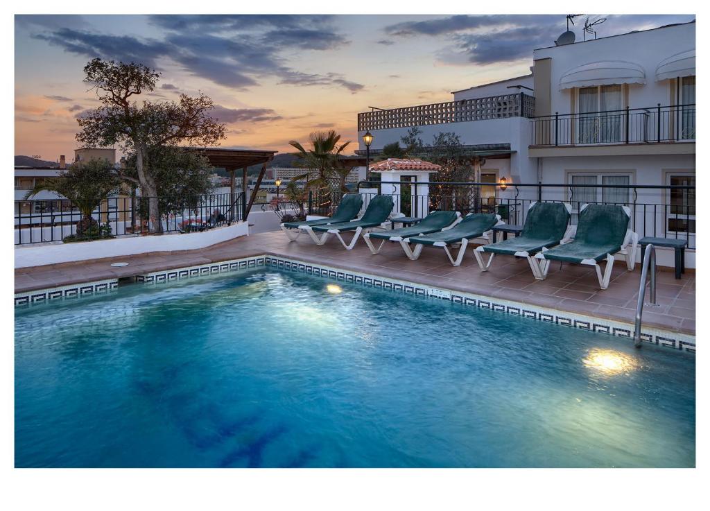 a swimming pool with chairs and a building at Hotel Ninays in Lloret de Mar