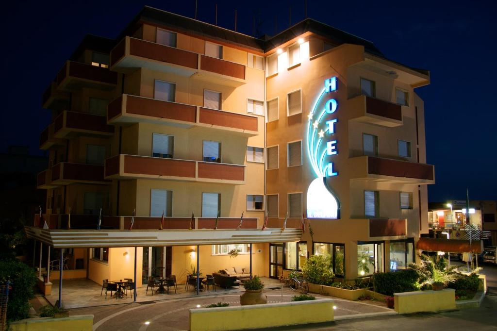 un bâtiment avec un panneau de néon devant lui dans l'établissement Hotel il Delfino, à San Vincenzo