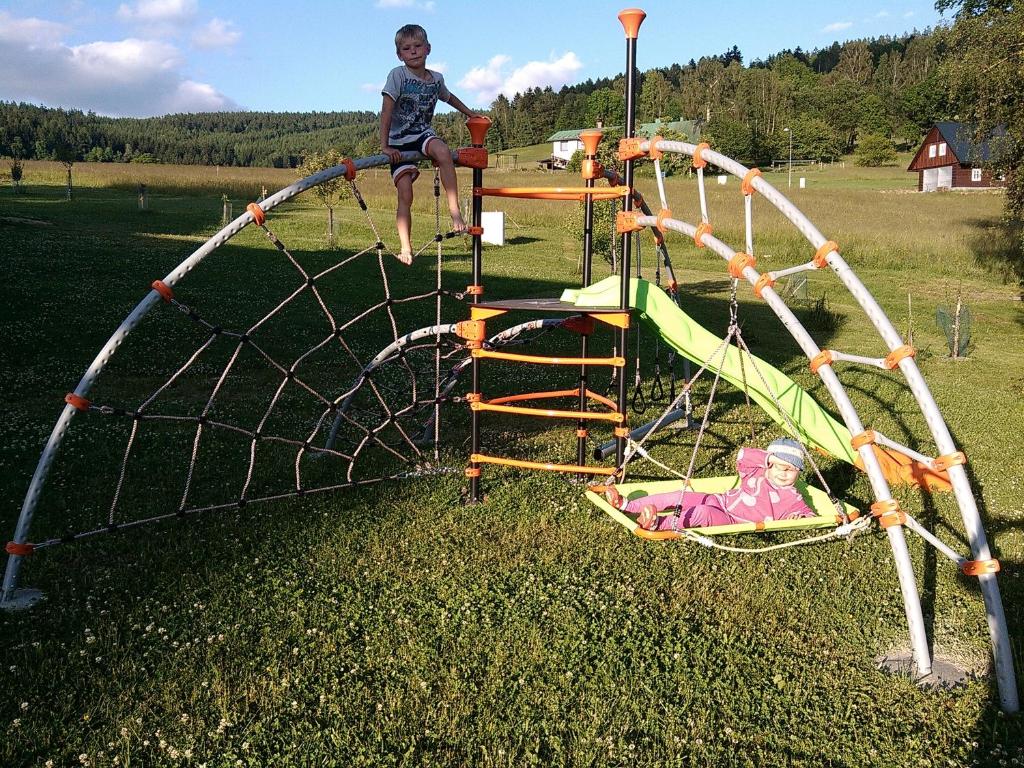 a young boy is sitting on a playground at Apartmány Kuřátko in Benecko