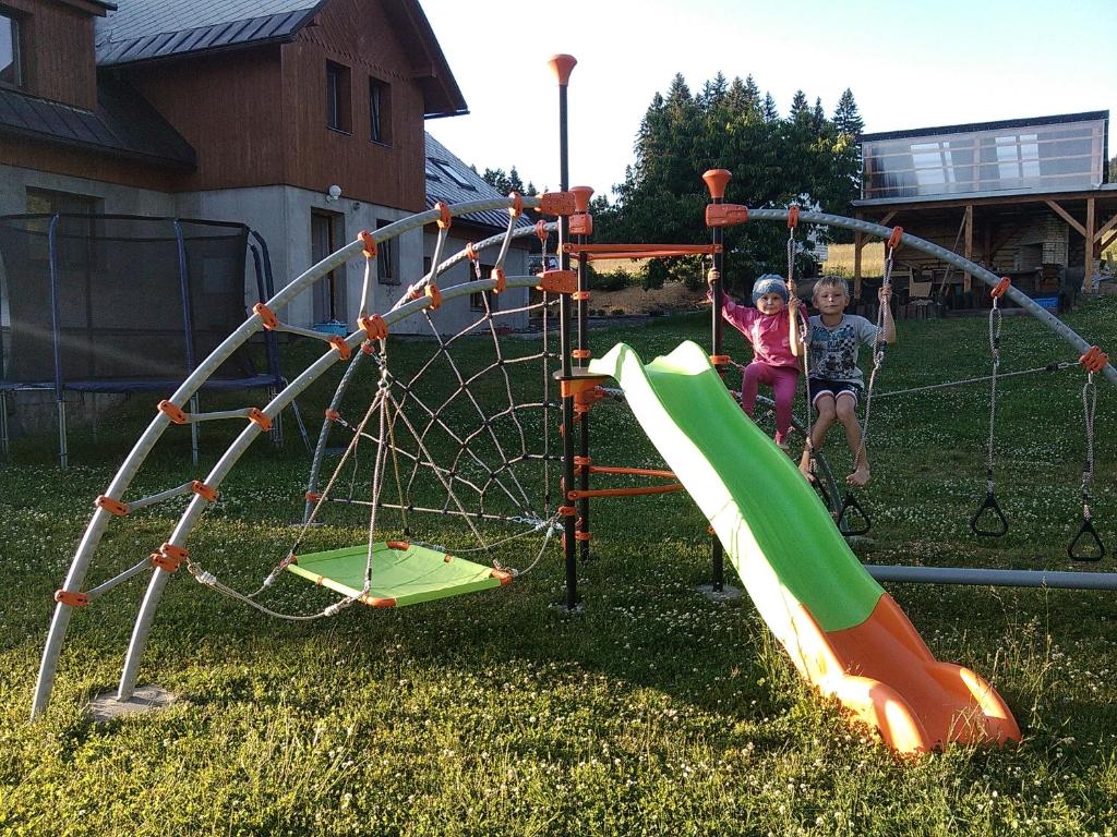 two children are playing on a playground at Apartmány Kuřátko in Benecko