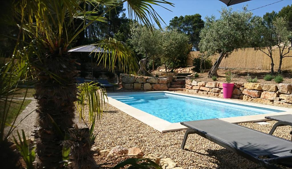 una piscina en un patio con una palmera en La Villa Aux Oliviers, en Flayosc