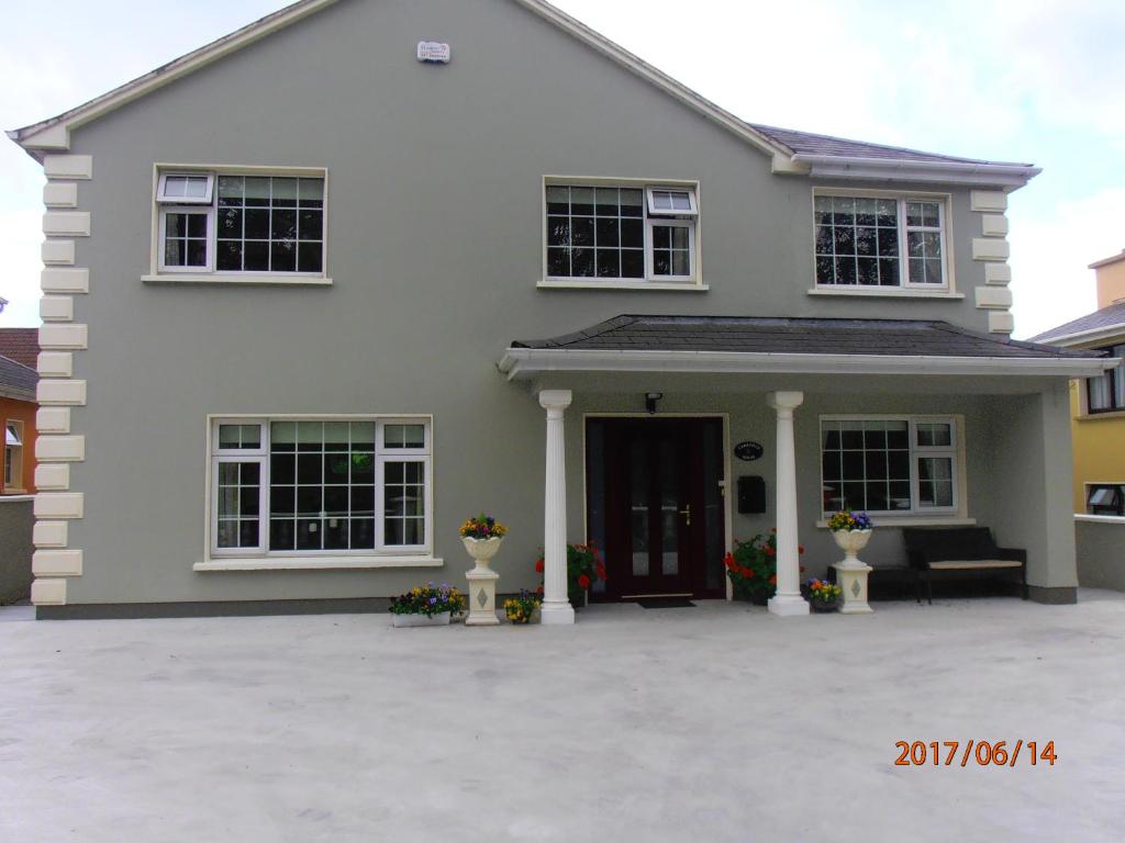 uma grande casa branca com um alpendre frontal em Larkfield House B&B em Killarney