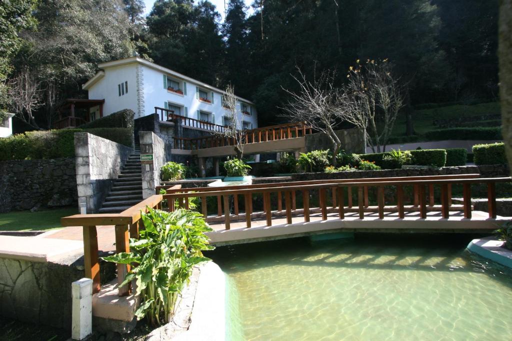 a wooden bridge over a pool in front of a house at Hotel El Paraiso in Mineral del Chico