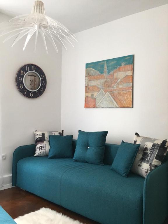 a blue couch in a living room with a clock on the wall at Squere 44 Apartment in Budva