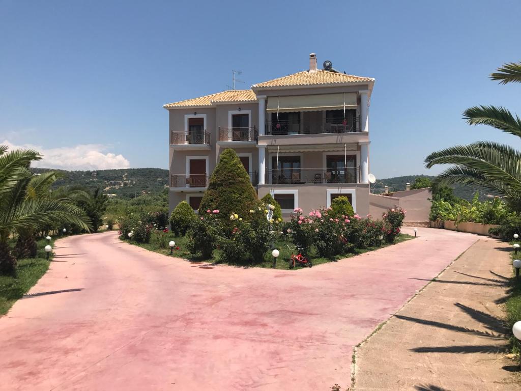 a house on a dirt road with trees and flowers at Apartments Irene in Gialova