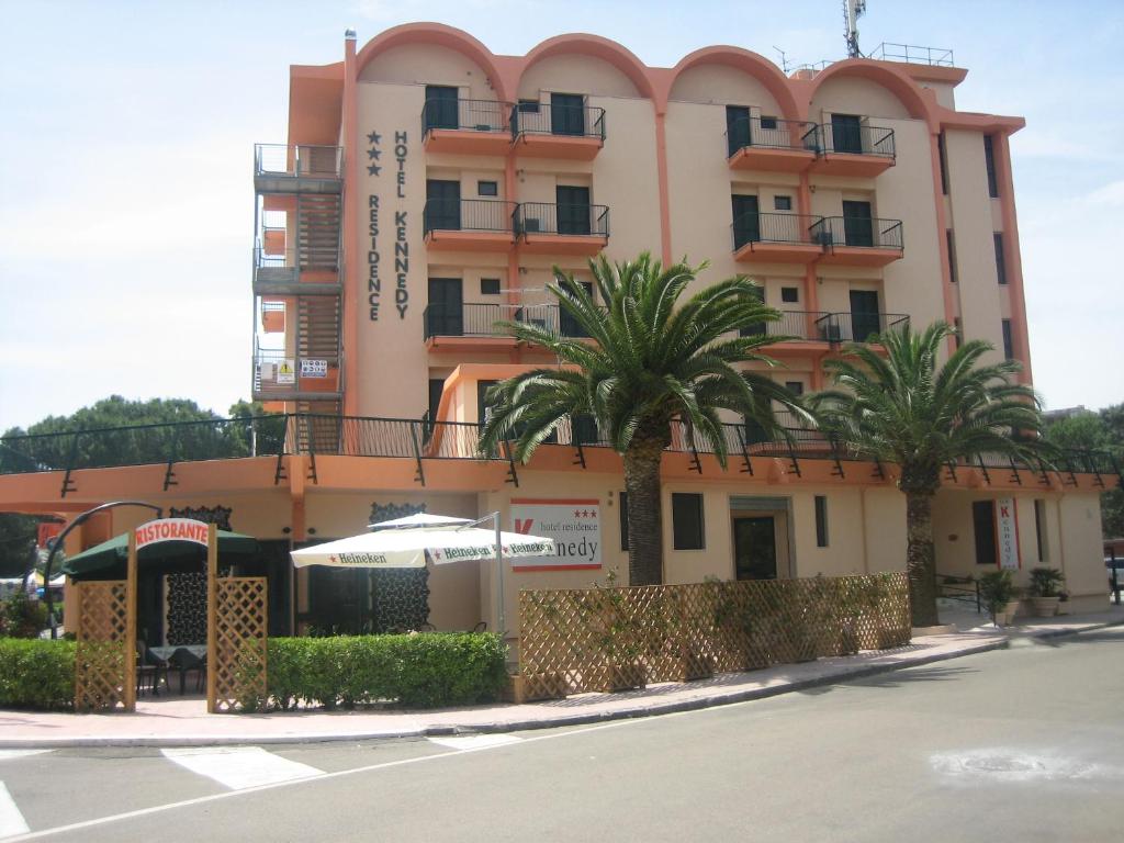 ein Gebäude mit Palmen vor einer Straße in der Unterkunft Hotel Kennedy in Metaponto