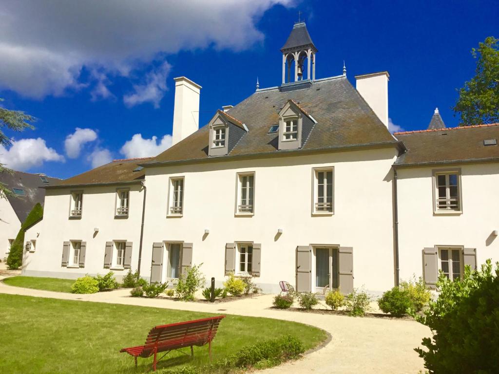 a white house with a red bench in front of it at La Pommeraie in Bruz