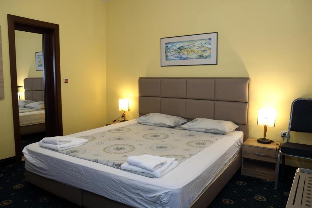 a bedroom with a large bed with two towels on it at Fenix Family Hotel in Blagoevgrad
