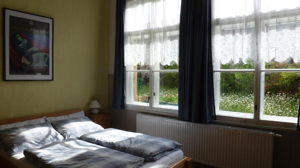 a bed sitting in a room with two windows at Alte Schule in Tambach-Dietharz