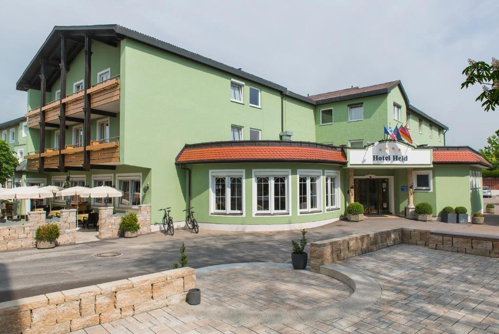 a green building with a patio in front of it at Hotel & Gasthof Richard Held in Regensburg